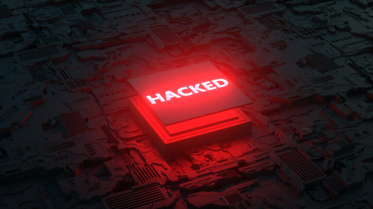 Czerwony procesor z napisem HACKED symbolizujący atak ransomware na firmową infrastrukturę IT